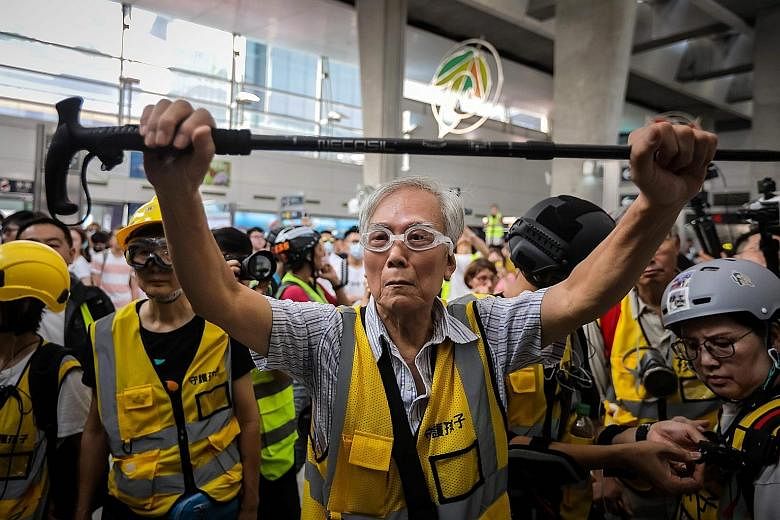 An 85-year-old volunteer, known as Grandpa Wong, holding up his walking stick to shield protesters from the police, along with other "silver hair" volunteers in Hong Kong's Tung Chung district last Saturday. They are part of a group called Protect th