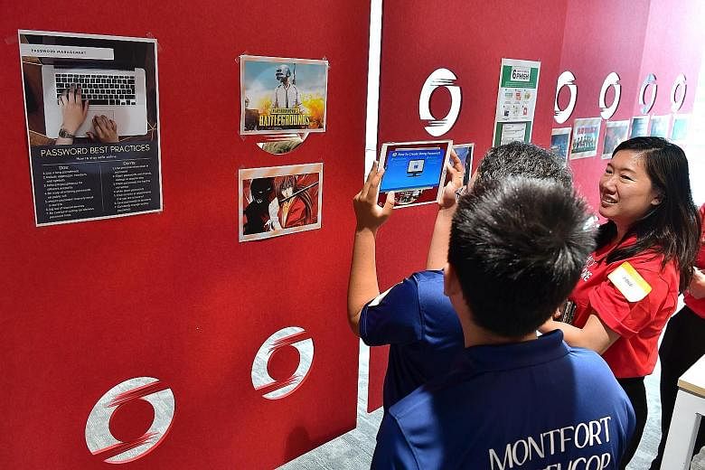 Participants at the coding and cyber-security workshop at Bank of Singapore's office in Raffles Place yesterday. For the AR activity, students used an app on a tablet to "scan" posters of video games put up on a wall, before watching a video and answ