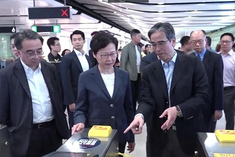 Chief Executive Carrie Lam touring the vandalised Central MTR station with officials. She examined electronic ticketing machines and boarded-up windows that were broken.