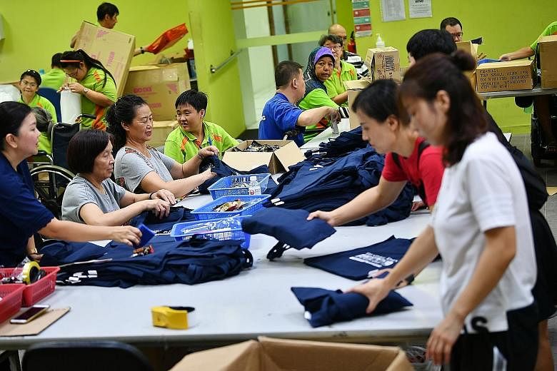 This year's race pack "haul" (above) includes two New Balance T-shirts, a water bottle, a wristband, muscle rub and fabric softener. Volunteers from LeCharity and people with disabilities (right) packing the race packs at SPD Ability Centre on Monday