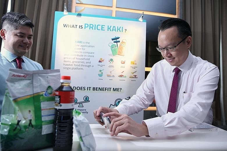 Dr Tan Wu Meng (at right), Senior Parliamentary Secretary for Trade and Industry, trying out the Price Kaki mobile app, developed by the Consumers Association of Singapore (Case), at Case's fund-raiser yesterday. With him was Case's deputy head of ap