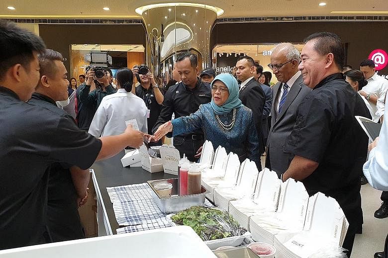 President Halimah Yacob interacting with staff from food and beverage brand Collin's at Singaporium, a consumer and lifestyle pop-up in Manila. She was accompanied by her husband, Mr Mohamed Abdullah Alhabshee (second from right). ST PHOTO: SUE-ANN T