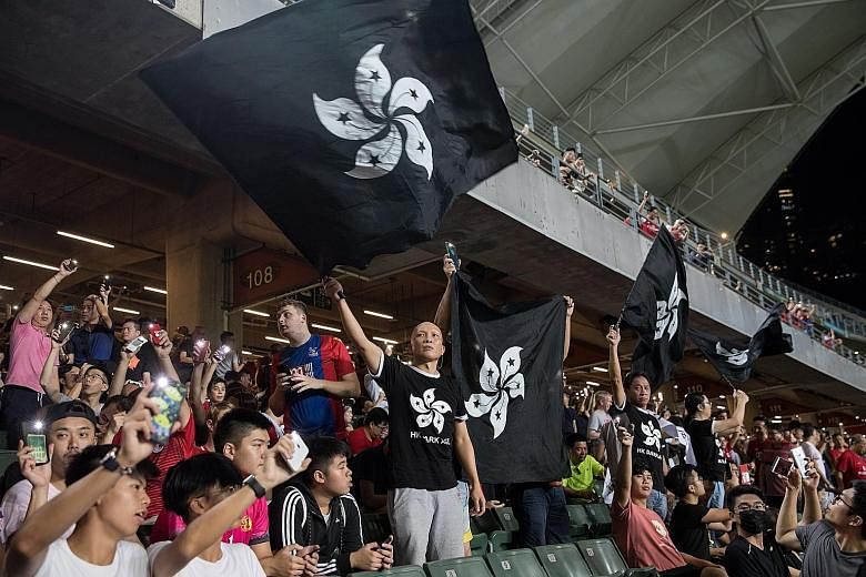 Hong Kong football fans waving black Bauhinia flags during a World Cup qualifier against Iran at Hong Kong Stadium on Tuesday. Ahead of the match, protesters booed the Chinese national anthem.