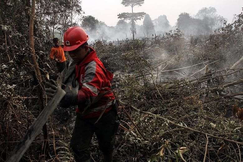 Indonesian firemen inspecting land in Kampar, Riau province, on Tuesday. More than a thousand hot spots have been spotted in Sumatra and Kalimantan. Malaysia saw its air quality worsen dramatically, with the air pollutant index in Rompin, Pahang, cli