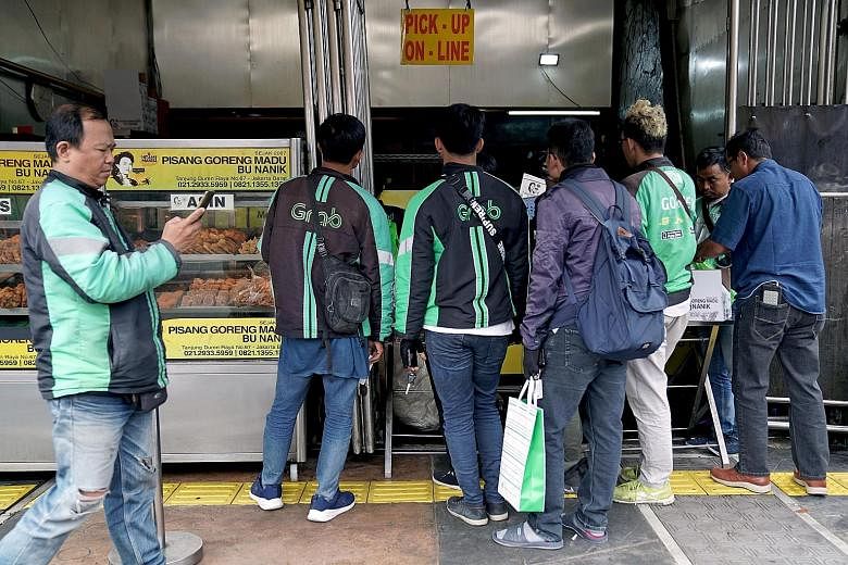 GrabFood drivers queueing up to collect orders at an eatery in Jakarta in July. Grab and Gojek are the top two start-up brands in South-east Asia, and they compete in areas such as financial services, e-commerce, ride hailing and food delivery. PHOTO