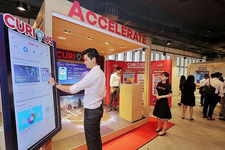 A staff member demonstrating Curious, Singtel's E-learning app for training and upskilling at the official opening of Singtel@8George yesterday. The four-storey office has classrooms, training facilities and interactive spaces for its staff to carry 