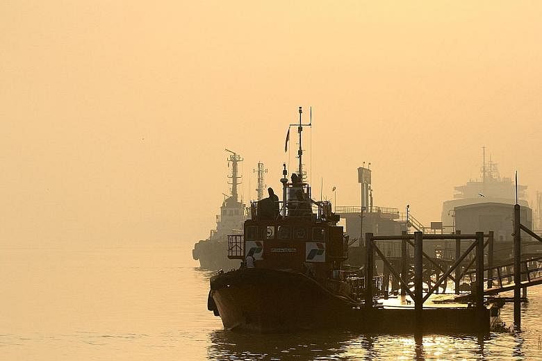 Left: Tugboats and ships moored in hazy conditions on the Musi River in Palembang, South Sumatra, yesterday. Above: Students with masks at a school in Puchong, Selangor, yesterday. Nationwide, there were over a dozen locations with Air Pollution Inde