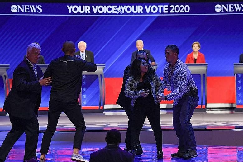 Protesters being escorted off the stage at the third Democratic primary debate in Houston, Texas, on Thursday, as (from left) Senator Bernie Sanders, former vice-president Joe Biden and Senator Elizabeth Warren look on. Ten presidential hopefuls part