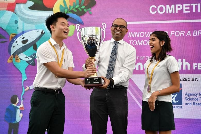 Dr Janil Puthucheary, Senior Minister of State for Transport and Communications and Information, presenting the trophy yesterday to Mr Kyle Tan and Ms Tara Kripalani from the St Joseph's Institution International team which clinched first place in th