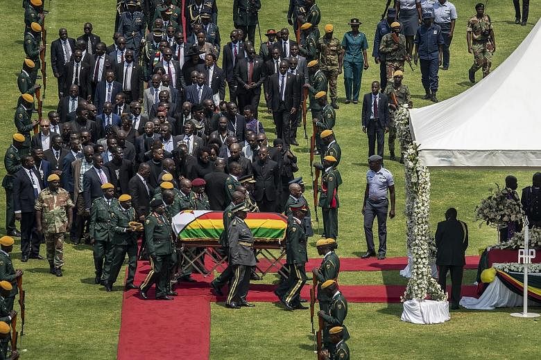 The casket of Zimbabwe's former president Robert Mugabe, covered by the national flag and attended by family and dignitaries, during his state funeral yesterday at the National Sports Stadium in the capital Harare. The final burial at a national monu