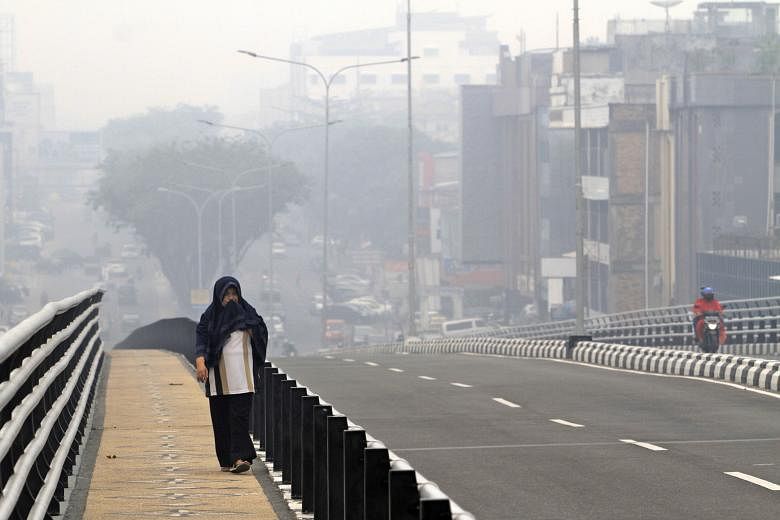 A woman covering her face as haze from forest fires blanketed Pekanbaru, Riau province, Indonesia, last Friday.