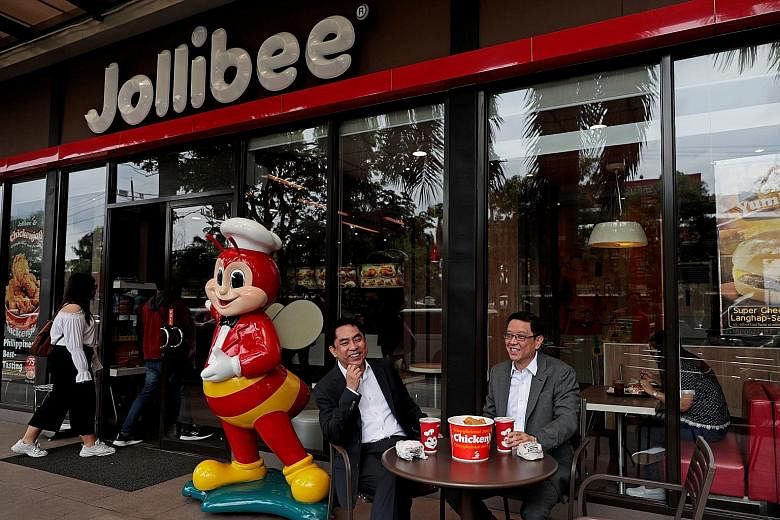 Jollibee Foods Corp chief executive Ernesto Tanmantiong and chief financial officer Ysmael Baysa (far left) outside a Jollibee branch in Pasig City, Metro Manila, Philippines, in July.