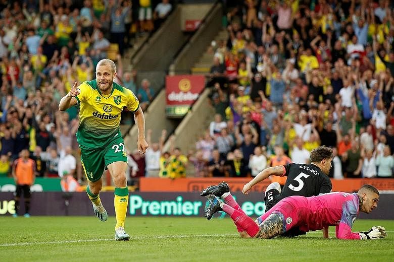Norwich City's Teemu Pukki celebrating after scoring his team's third goal on Saturday, leaving the crestfallen City defender John Stones and goalkeeper Ederson looking for answers.