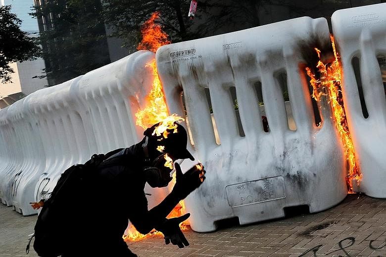 Police using water cannon outside the government headquarters in Hong Kong to disperse protesters yesterday. One water cannon was spraying blue jets of water, which make protesters easier to identify later. A protester on fire after throwing a Moloto
