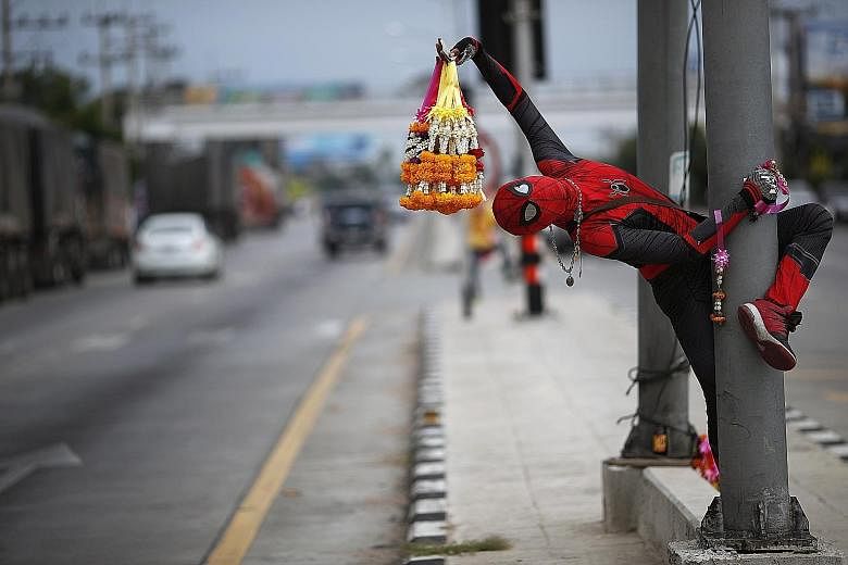 Thai street vendor Wasan Ketsuwan swings by, dressed up in a Spider-Man costume, to sell garlands of flowers to motorists on a highway in the Tha Yang district of Thailand's Phetchaburi province. He and his elder brother create various superhero cost