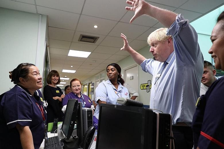 British Prime Minister Boris Johnson meeting members of the staff during a visit to a hospital in east London yesterday.