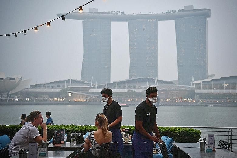 Restaurants with alfresco dining overlooking Marina Bay, such as OverEasy (above) at One Fullerton, say customers have been staying away since last weekend. Staff at OverEasy now wear masks to protect themselves.