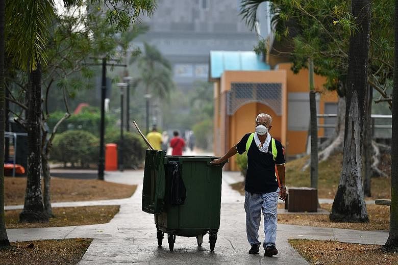 Cleaner Ng Siew Chuan, 78, wearing a face mask on the job at Tampines Central Park yesterday at around 9am. The 24-hour PSI reading in the eastern part of Singapore was 109 at 8am yesterday and the one-hour PM2.5 reading was 96. ST PHOTO: LIM YAOHUI
