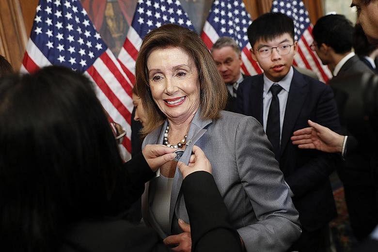 US House Speaker Nancy Pelosi being given a lapel pin by a Hong Kong activist in Washington on Wednesday. Behind Ms Pelosi is Hong Kong activist Joshua Wong.
