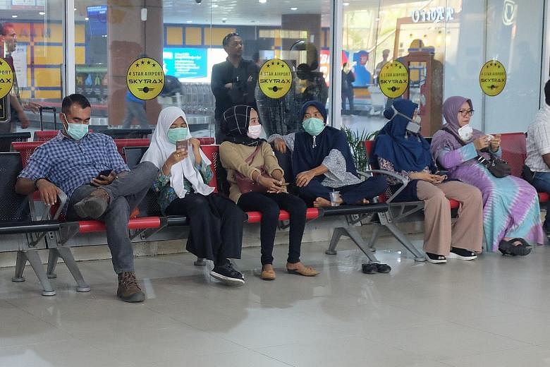 Travellers wearing masks at Pekanbaru's international airport in Riau province yesterday. Two aircraft were yesterday deployed in the city with the discovery of dense clouds that could be seeded to induce rain. ST PHOTO: KHALID BABA