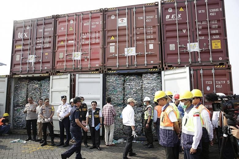 Indonesian officials with the containers of plastic waste meant for recycling, at a press briefing at Jakarta International Container Terminal on Wednesday. Indonesia says the waste was found to contain hazardous substances. PHOTO: EPA-EFE