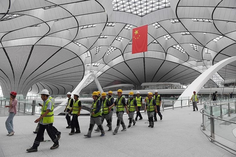 Workers walking through the terminal building of the new Beijing Daxing International Airport. The airport is expected to handle 72 million passengers a year by 2025. The long-term goal is for it to handle 100 million passengers and four million tonn