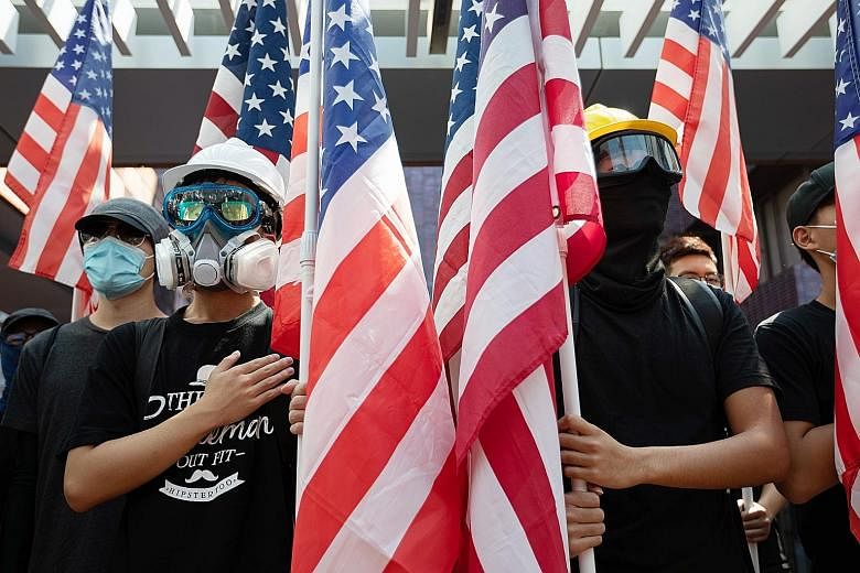 Protesters with US flags during a rally in Hong Kong yesterday. An Amnesty International report, based on interviews with detainees, says the police used retaliatory violence. The police have rejected the charges, saying the report was missing key de