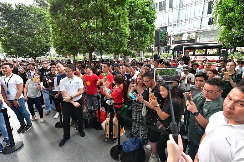 Mr Ryan Le, 28, from Ho Chi Minh, with iPhones bought by his compatriots at the Apple store in Orchard. He himself bought two iPhones. A crowd queueing outside Apple's Orchard Road flagship store before the launch of the latest iPhone 11 series yeste