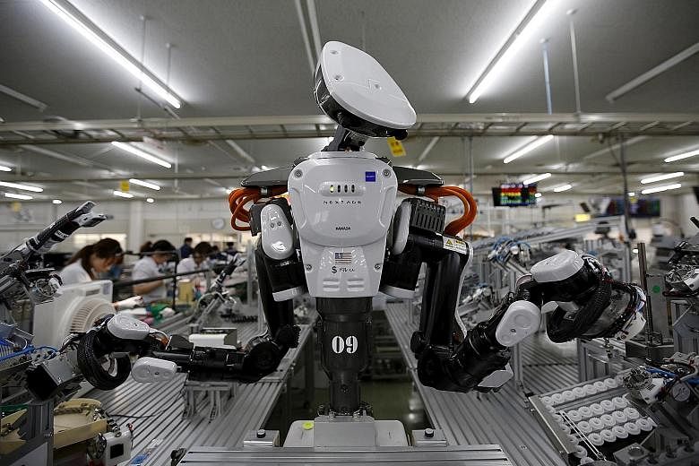 A humanoid robot working side by side with employees in the assembly line of a factory in Kazo, north of Tokyo.