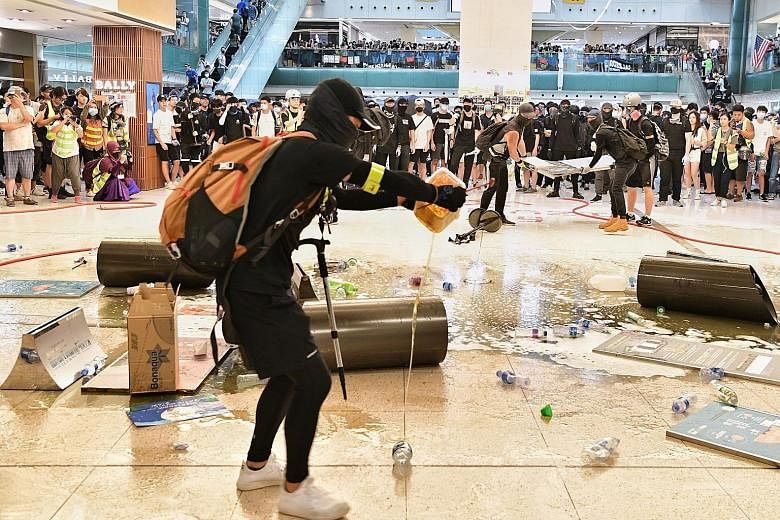 A protester pouring oil on the floor of the New Town Plaza mall in Hong Kong yesterday, to make it slippery and slow police advancement. ST PHOTO: CHONG JUN LIANG
