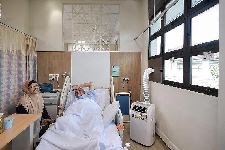 Senior security officer Haron Jasmin is safe at Alexandra Hospital with a portable air-conditioning unit and an air purifier (blue) providing ventilation. Beside him is his wife Rabiah Tik, 65, who was visiting yesterday. ST PHOTO: KUA CHEE SIONG Peo