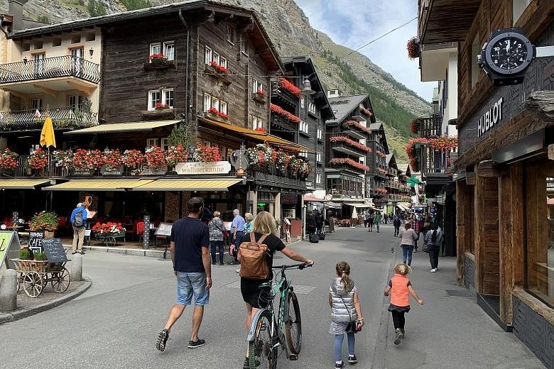 Bahnhofstrasse, the main street leading to and from Zermatt's train station. Take a series of trains (left) from Interlaken to view mountains such as Monch and Jungfrau, both over 4,000m high. The writer (above) paragliding over trees, houses and fie