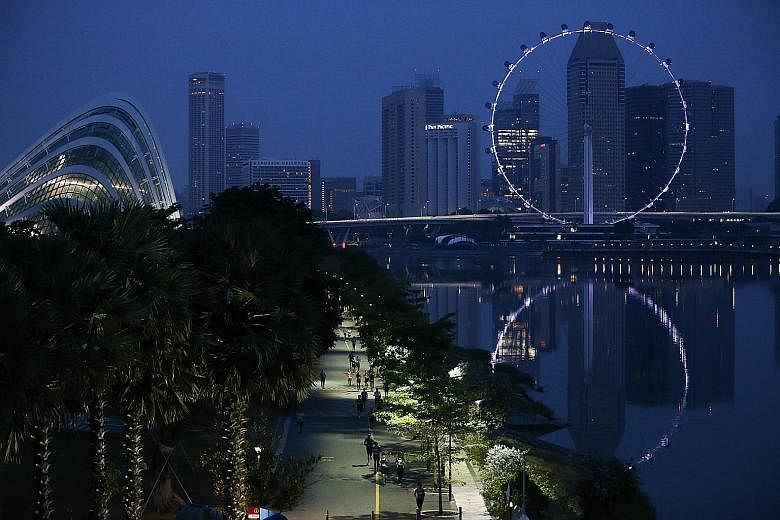 Runners in the 18.45km race along Marina Bay next to Gardens by the Bay as day breaks.