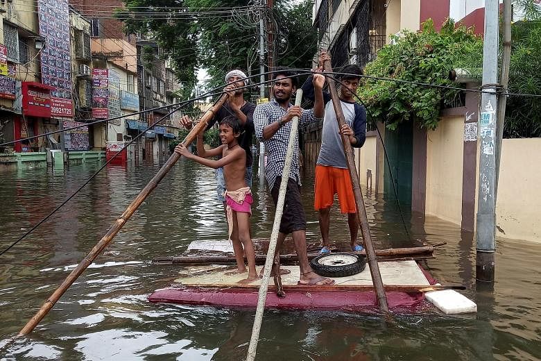 People using a makeshift raft in a flooded neighbourhood of Patna in the eastern state of Bihar yesterday. Heavy rain has killed at least 113 people in India's Uttar Pradesh and Bihar states over the past three days, officials said yesterday as flood