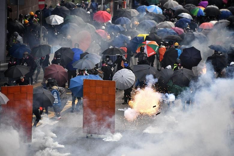 Protesters retreating as a tear gas canister exploded in Hong Kong on Sunday. The writer says that what started as a civilian protest against an extradition law has now turned into something far more sinister. It is no more just people versus the gov