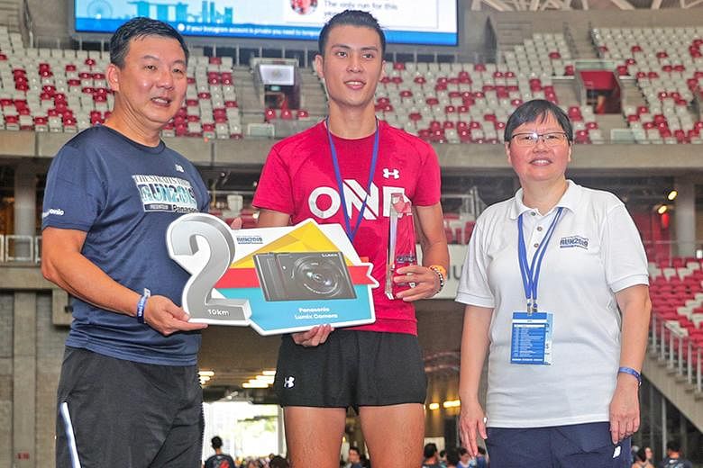 Banjamin Quek (centre), runner-up in the 10km race at The Straits Times Run last Sunday, received his trophy from ST sports editor Lee Yulin and his prize from Nicholas Chua, director, customer service, Panasonic Singapore. Quek took home a $1,099 Pa