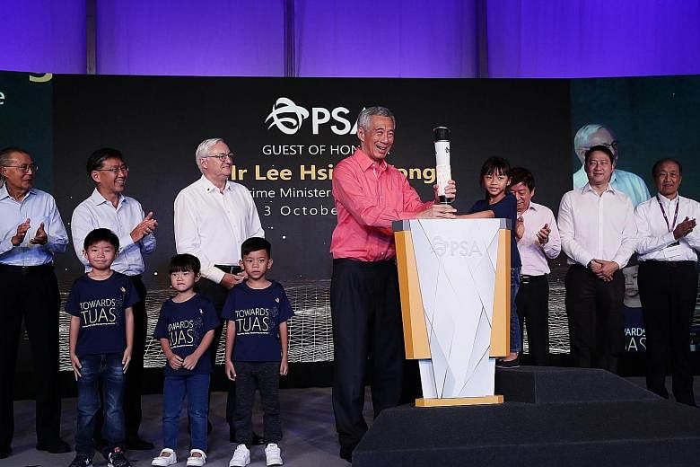 Prime Minister Lee Hsien Loong and five-year-old Hana Romiza Muhamad Reduan placing a torch on the grounds of Tuas Port yesterday to symbolise the start of a new chapter in Singapore's maritime history. With them were (from left) former PSA chairman 
