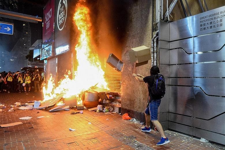A protester starting a fire at the Causeway Bay MTR station entrance in Hong Kong last night following the government's invocation of an emergency power banning the use of face masks in public assemblies. PHOTO: AGENCE FRANCE-PRESSE