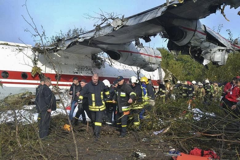 Emergency services crew at the site of the plane crash in Lviv, western Ukraine, yesterday. The Antonov-12 plane, which was carrying eight people, took off in Spain and crashed while coming in to land 1.5km from the Lviv airport runway. The surviving