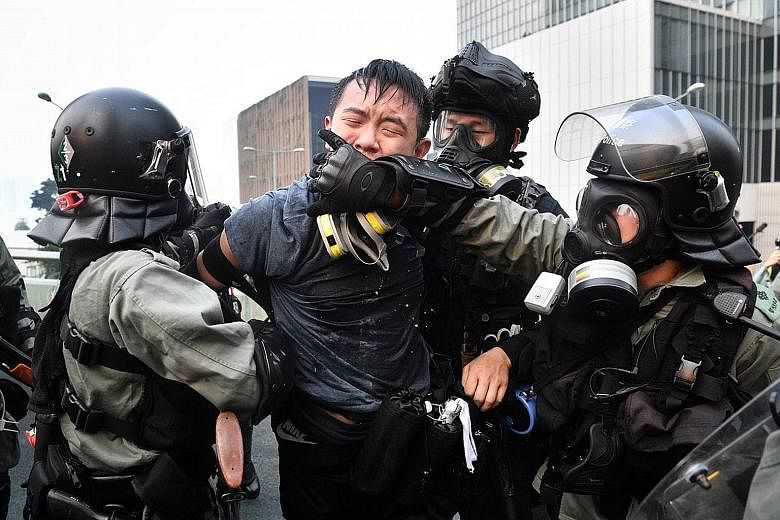 Police covering the mouth of a protester they arrested to stop him from speaking to the media in Harcourt Road on Sept 29. Clashes between protesters and police have led to unbridled anger against what was once known as Asia's finest force. Protester