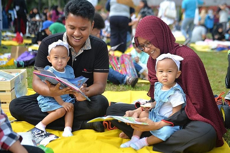 Civil servant Helmi Rosman and his wife Nurkamaliah Omar, both 31, reading with their one-year-old twin daughters Naura (left) and Husna. They were among 1,500 people who turned up for Reading @ The Gardens at Gardens by the Bay yesterday morning, as