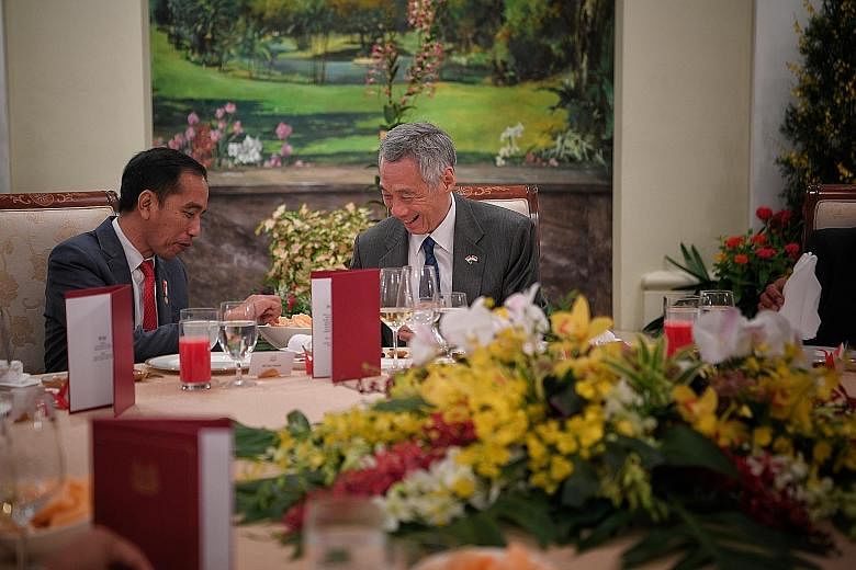 Indonesian President Joko Widodo and Prime Minister Lee Hsien Loong sharing a light moment over keropok and sambal at the start of their dinner yesterday at the Istana, during this year's Singapore-Indonesia Leaders' Retreat. ST PHOTO: MARK CHEONG