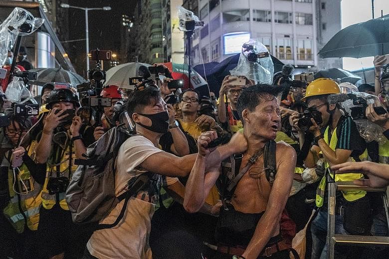 Above: A masked man attacking another man in Kowloon on Sunday, in front of journalists. In recent weeks, some protesters have targeted property and individuals with greater ferocity. Left: Protesters setting fire to an entrance of the Admiralty MTR 