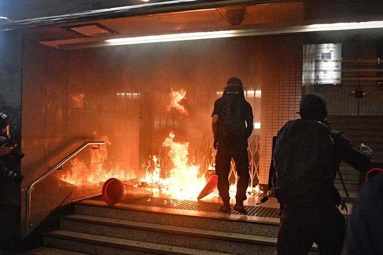 Above: A masked man attacking another man in Kowloon on Sunday, in front of journalists. In recent weeks, some protesters have targeted property and individuals with greater ferocity. Left: Protesters setting fire to an entrance of the Admiralty MTR 