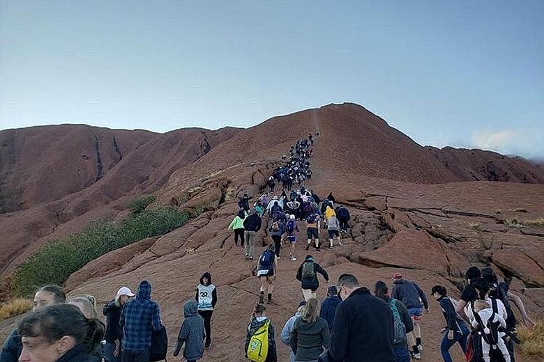 Tourists crowding a trail as they attempt to climb Uluru in Australia's Northern Territory before an Oct 26 ban takes effect.