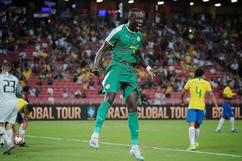 Above: A joyous Famara Diedhiou after converting a penalty to equalise for the African side. Left: Neymar evading a tackle by Senegal's Kalidou Koulibaly in last night's international friendly at the National Stadium. The Brazil star notched his cent