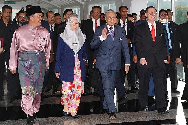 Malaysia's Prime Minister Mahathir Mohamad waving on arrival at Parliament for the budget presentation by Finance Minister Lim Guan Eng (right) yesterday. Accompanying them were Deputy Finance Minister Amiruddin Hamzah and Deputy Prime Minister Wan A