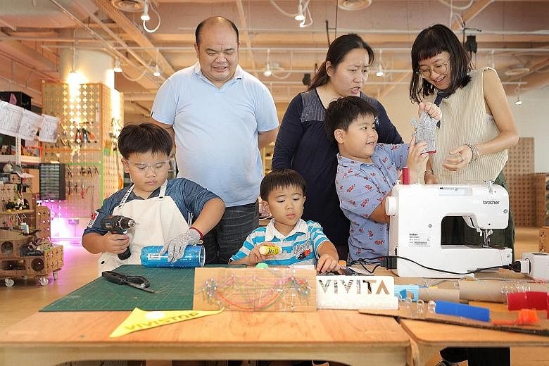 Mr Robert Sim and Ms Carol Lim let their son Ian (left, with his brothers Egan and Eli) keep up with his creative projects at VIVISTOP during exam time. Staff member Therese Heng (right) is teaching Eli how to sew.