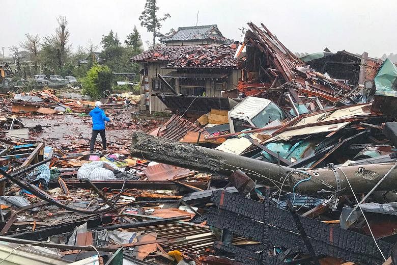 The debris of houses damaged by Typhoon Hagibis in Ichihara, Chiba prefecture, east of Tokyo, yesterday. Tokyo came to a virtual standstill yesterday, as train services were halted and malls and eateries shuttered. Supermarket shelves were emptied by