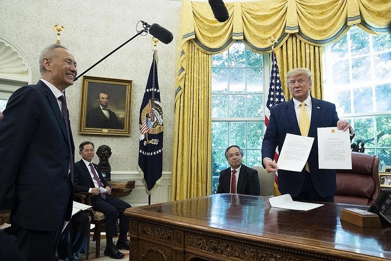 US President Donald Trump with a letter from Chinese President Xi Jinping, presented by China's top trade negotiator Liu He (left), in Washington on Friday. The US and China agreed to the first phase of a deal to end the trade war, with the agreement